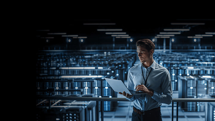 Man monitoring laptop in server farm