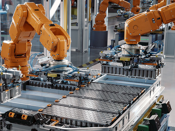 Three orange industrial robots assemble EV battery on automated production Line inside automotive plant